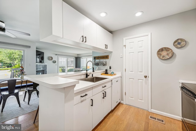 kitchen with white cabinetry, white dishwasher, kitchen peninsula, and sink