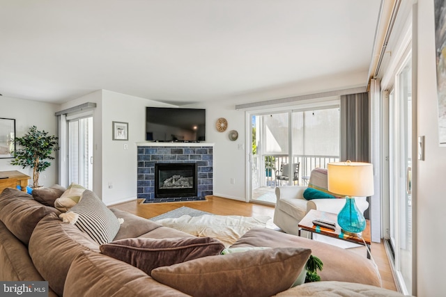 living room featuring a stone fireplace and light hardwood / wood-style floors