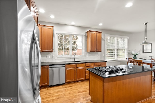 kitchen with a kitchen island, sink, hanging light fixtures, light hardwood / wood-style floors, and stainless steel appliances