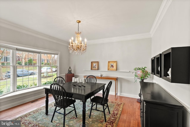 dining area with crown molding, a notable chandelier, and light wood-type flooring