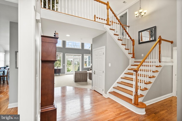 stairway with a notable chandelier, hardwood / wood-style floors, and a high ceiling