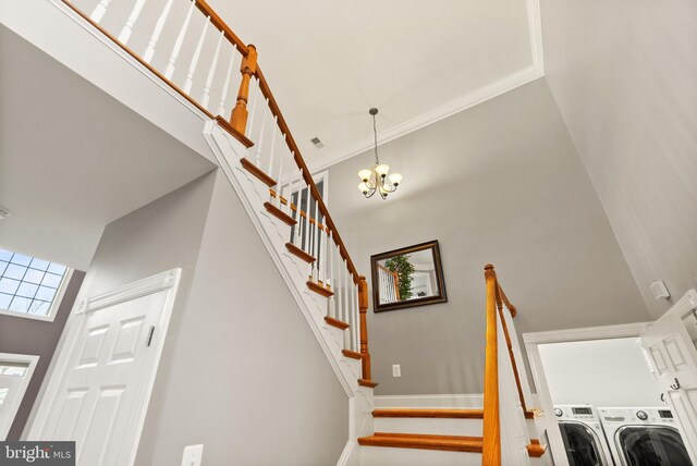 stairs featuring crown molding, a notable chandelier, a towering ceiling, and washing machine and dryer