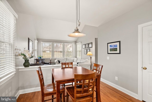 dining space featuring vaulted ceiling and light hardwood / wood-style floors