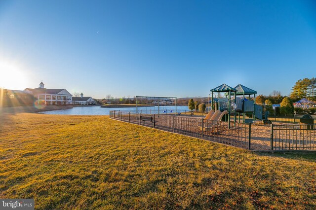 view of playground with a water view and a lawn