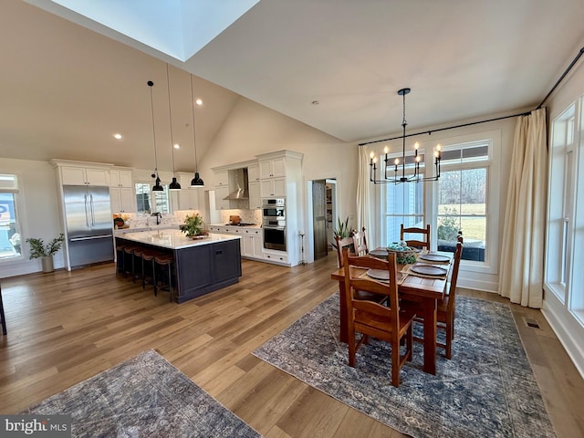 dining space with high vaulted ceiling, hardwood / wood-style floors, and a notable chandelier