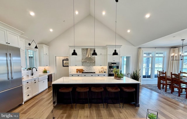 kitchen with sink, hanging light fixtures, stainless steel appliances, a large island, and white cabinets