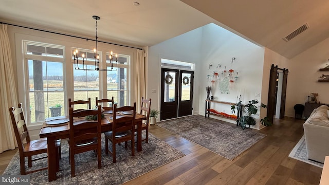 dining room featuring a barn door, dark hardwood / wood-style floors, a notable chandelier, and french doors