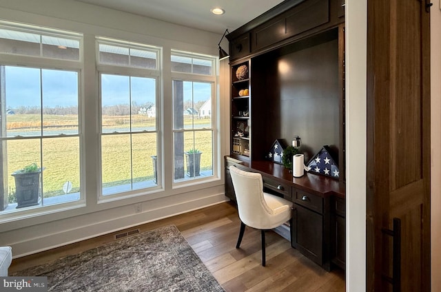 office featuring built in desk and hardwood / wood-style floors