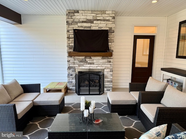 living room featuring a stone fireplace, wood ceiling, and wood walls