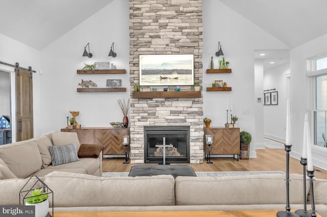 living room featuring wood-type flooring, a barn door, a stone fireplace, and baseboard heating