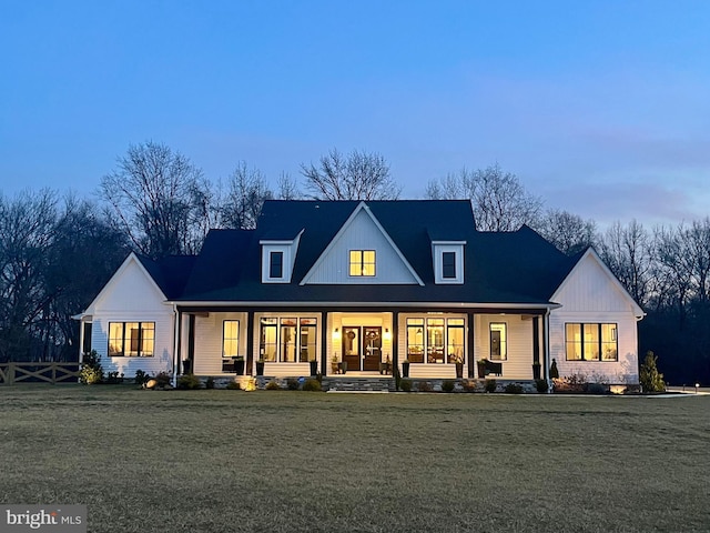 back house at dusk featuring a yard and covered porch