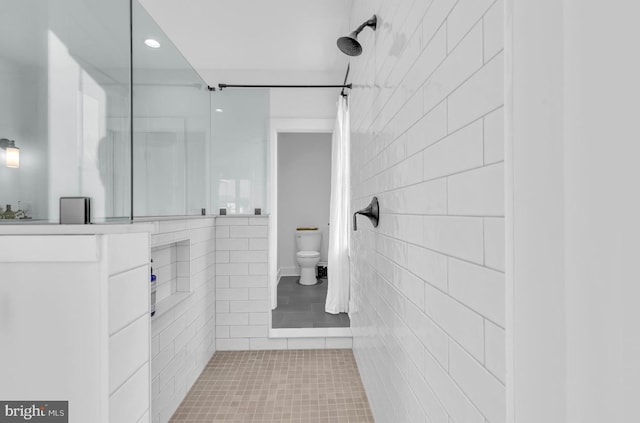 bathroom featuring tile patterned flooring, a shower, tile walls, and toilet