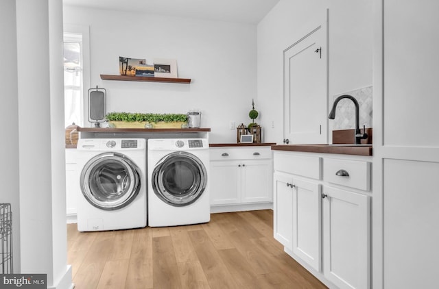 laundry room with sink, light hardwood / wood-style flooring, cabinets, and washing machine and clothes dryer