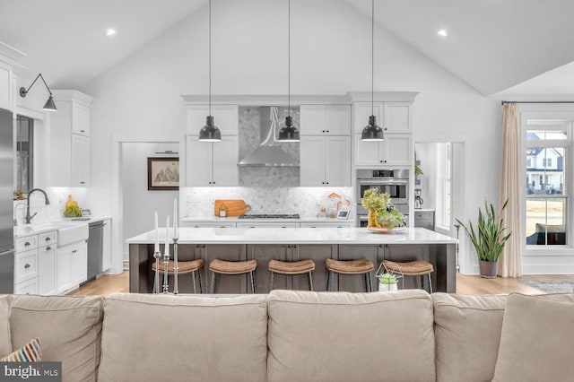 kitchen with a center island, decorative light fixtures, and wall chimney exhaust hood