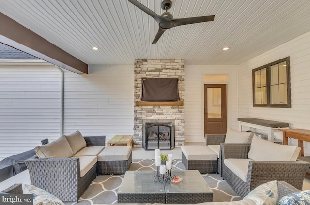 living room with ceiling fan, beamed ceiling, and an outdoor stone fireplace