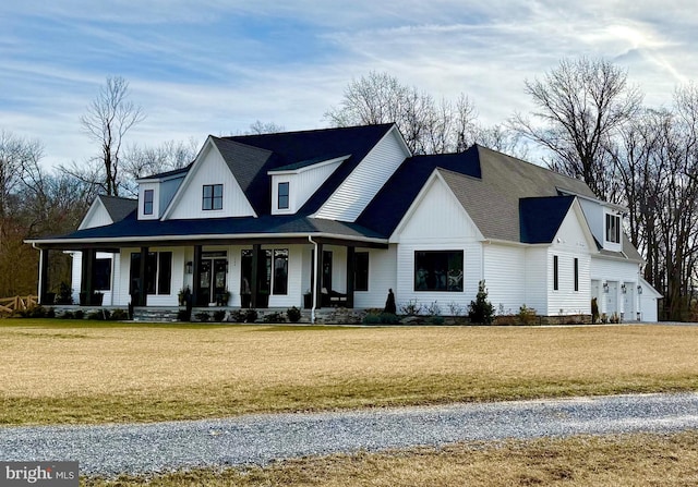 modern inspired farmhouse with a garage, covered porch, and a front lawn