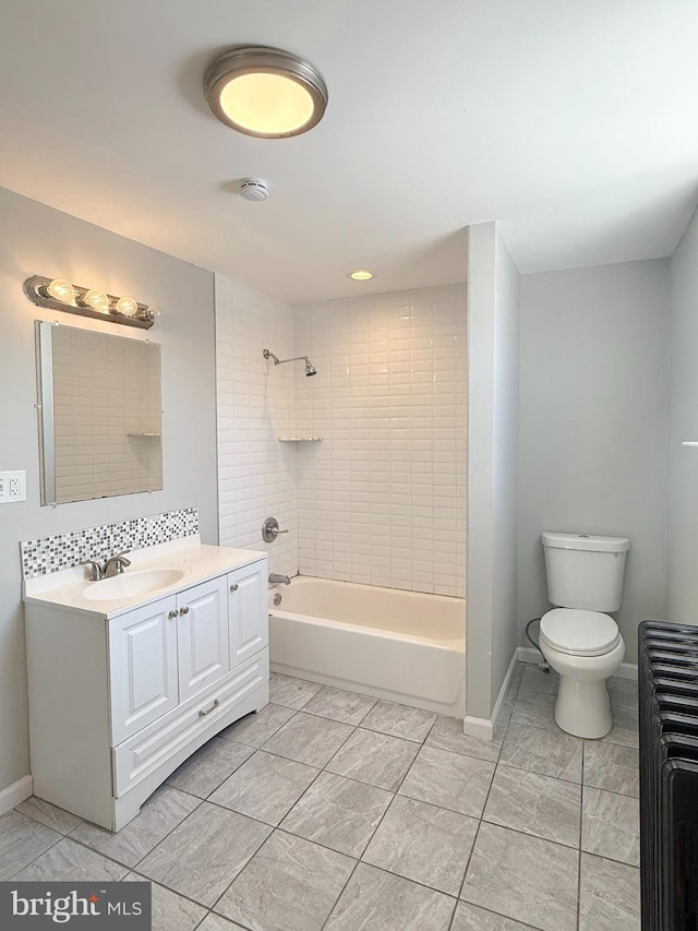 full bathroom featuring tiled shower / bath, radiator, vanity, and toilet