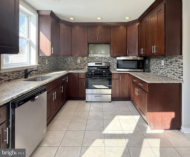 kitchen with light stone countertops, appliances with stainless steel finishes, sink, and light tile patterned floors