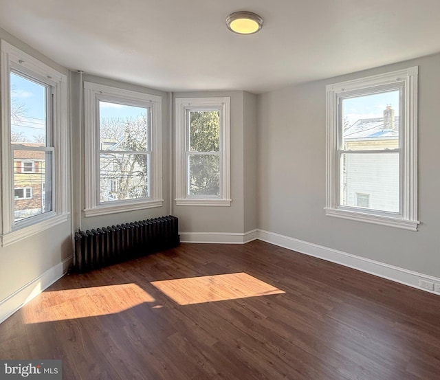 unfurnished room featuring dark hardwood / wood-style flooring and radiator heating unit