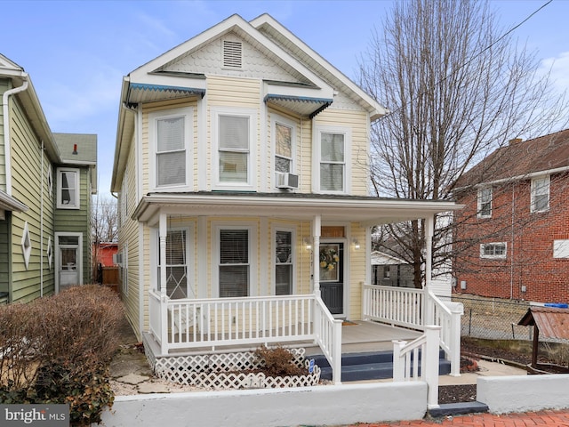 view of front of home with covered porch, cooling unit, and fence