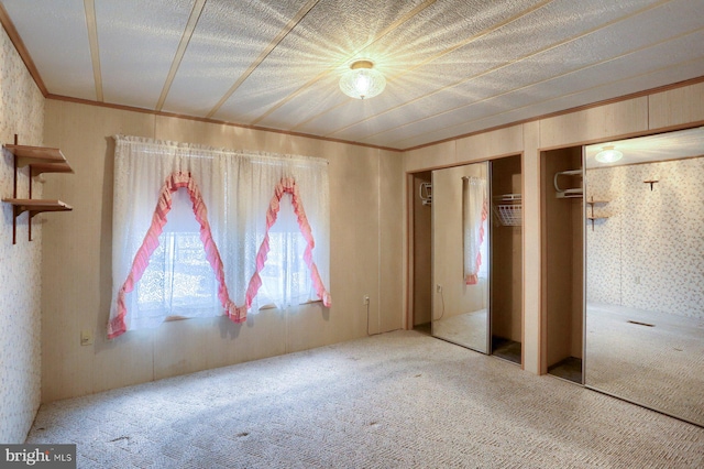 unfurnished bedroom featuring crown molding, multiple closets, and carpet flooring