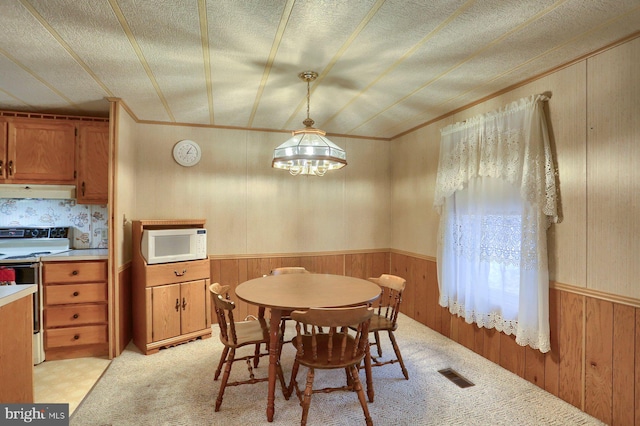 dining area featuring a textured ceiling and wooden walls