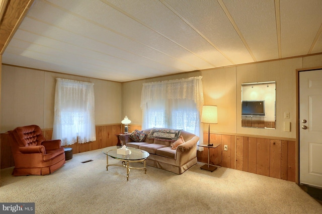 carpeted living room with crown molding, a textured ceiling, and wooden walls