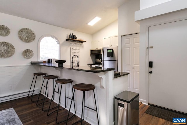 kitchen with dark hardwood / wood-style floors, kitchen peninsula, white cabinets, and appliances with stainless steel finishes