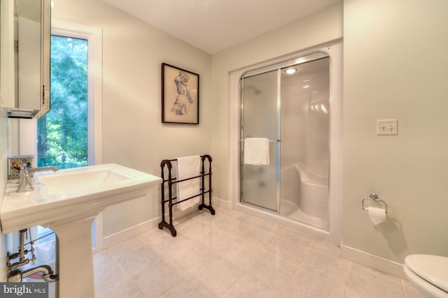 bathroom featuring tile patterned floors, toilet, and a shower with door