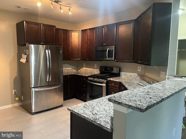 kitchen featuring light stone counters, kitchen peninsula, and appliances with stainless steel finishes