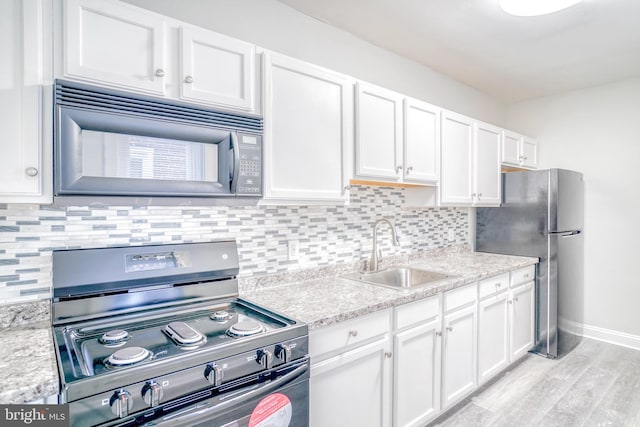 kitchen featuring sink, stainless steel fridge, stove, tasteful backsplash, and white cabinets