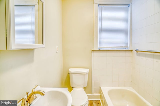 bathroom with sink, a washtub, and toilet