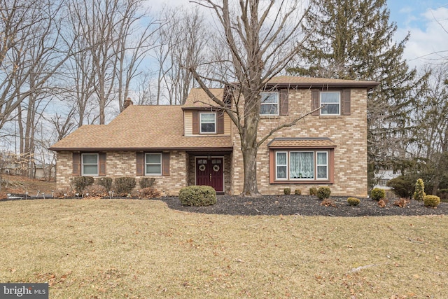 traditional-style home featuring a shingled roof, a front yard, brick siding, and a chimney