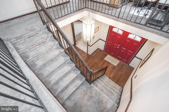 entryway with stairs, wood finished floors, and a towering ceiling