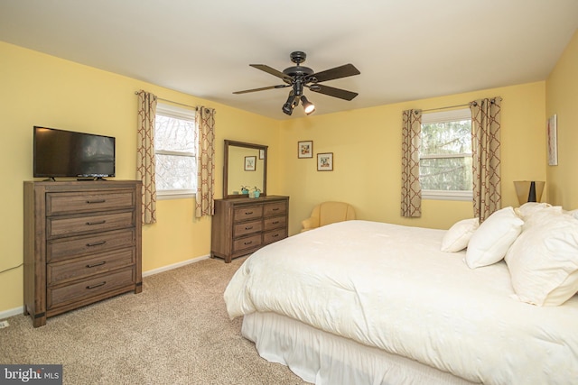 bedroom with baseboards, multiple windows, and light colored carpet