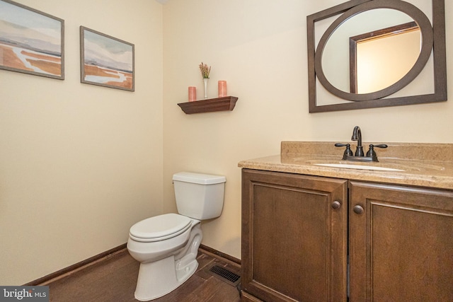 bathroom with visible vents, toilet, vanity, wood finished floors, and baseboards