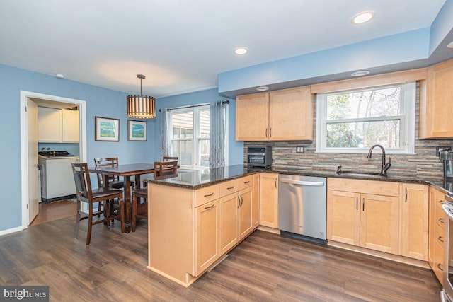 kitchen featuring a peninsula, a sink, stainless steel dishwasher, light brown cabinetry, and washer / dryer