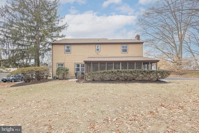 rear view of house with a sunroom, a lawn, and a chimney