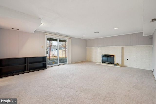 unfurnished living room with crown molding, light colored carpet, a fireplace, and visible vents