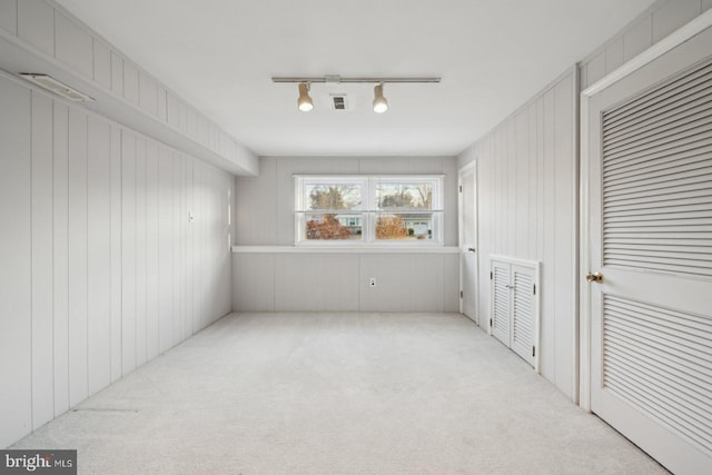 spare room with rail lighting, visible vents, and light colored carpet