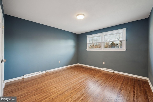 unfurnished room with visible vents, baseboards, and wood finished floors