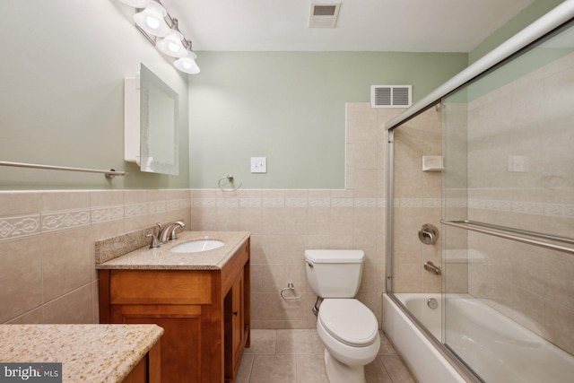 bathroom featuring visible vents, toilet, vanity, and combined bath / shower with glass door