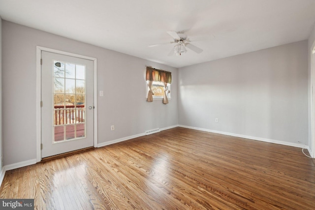 spare room with a ceiling fan, visible vents, baseboards, and wood finished floors