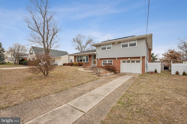 tri-level home with a front yard, fence, concrete driveway, and brick siding