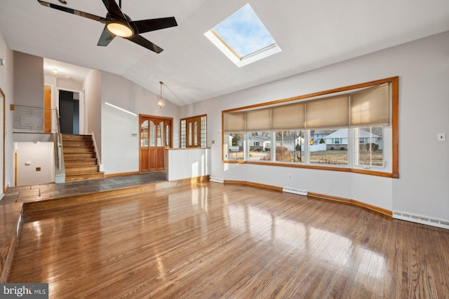 unfurnished living room featuring visible vents, stairway, lofted ceiling with skylight, ceiling fan, and wood finished floors