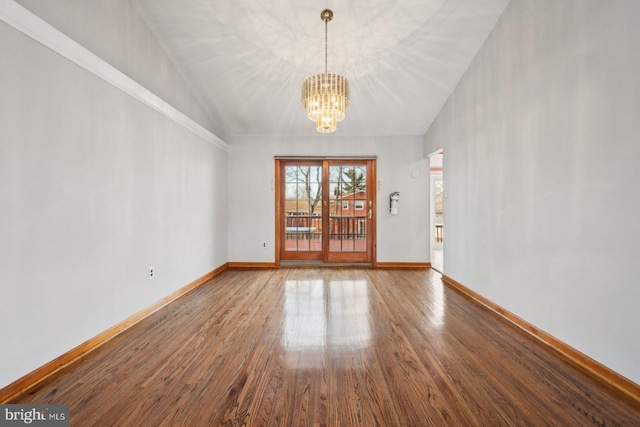 spare room with lofted ceiling, baseboards, a chandelier, and wood finished floors