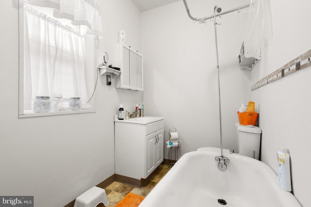 bathroom featuring vanity, a washtub, and toilet