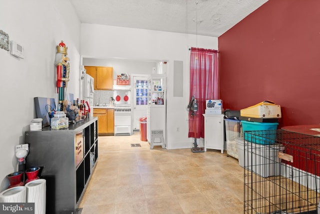 kitchen featuring white refrigerator, range, a textured ceiling, and decorative backsplash