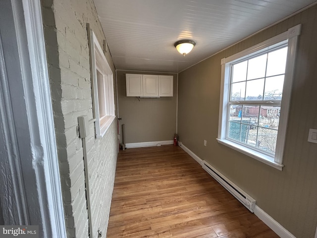 hall with a baseboard heating unit and light wood-type flooring