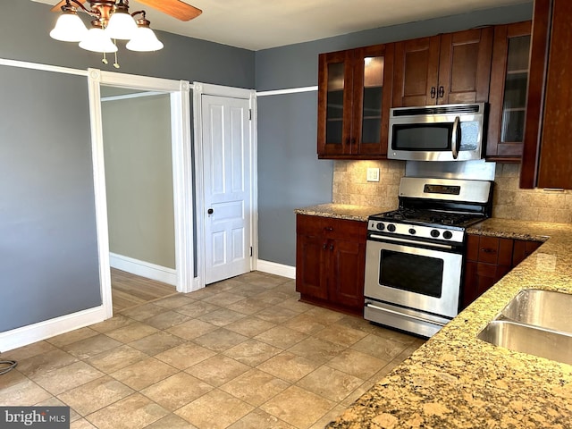 kitchen with ceiling fan, appliances with stainless steel finishes, light stone countertops, and backsplash